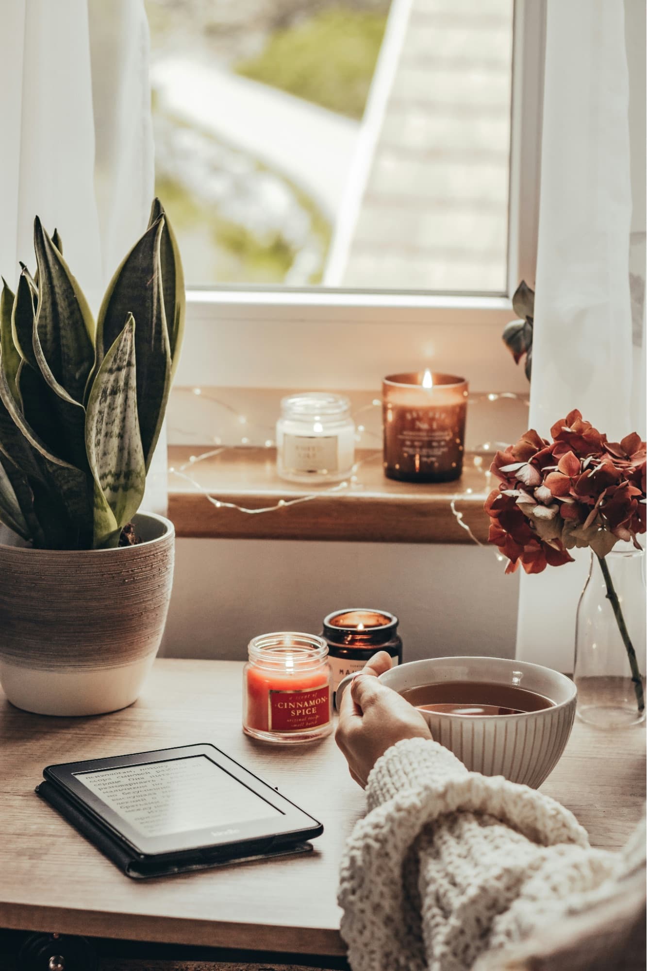 A quiet morning by a window with tea, a candle, and a book